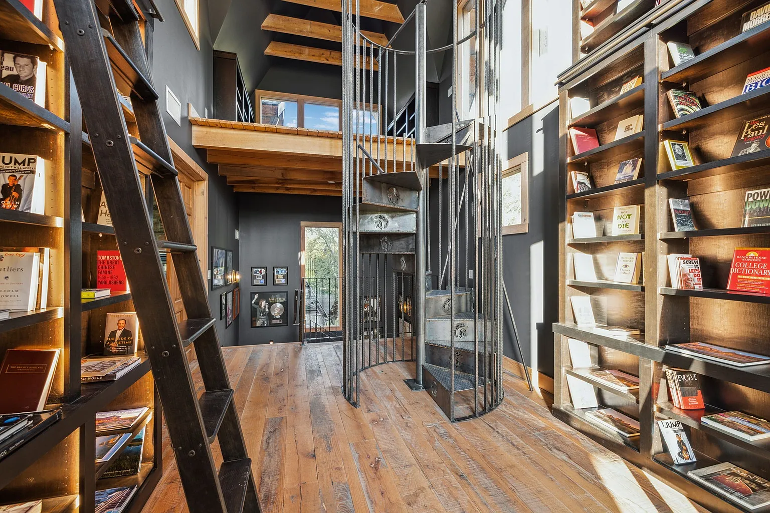A two-story library is lined with floor-to-ceiling bookshelves that stretch to an upper loft.