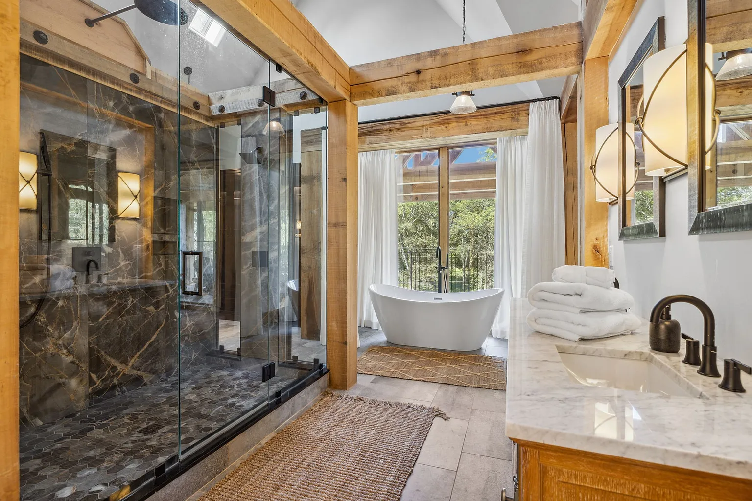 Bathroom with a large glass-enclosed shower in dramatic dark stone, a freestanding soaking tub