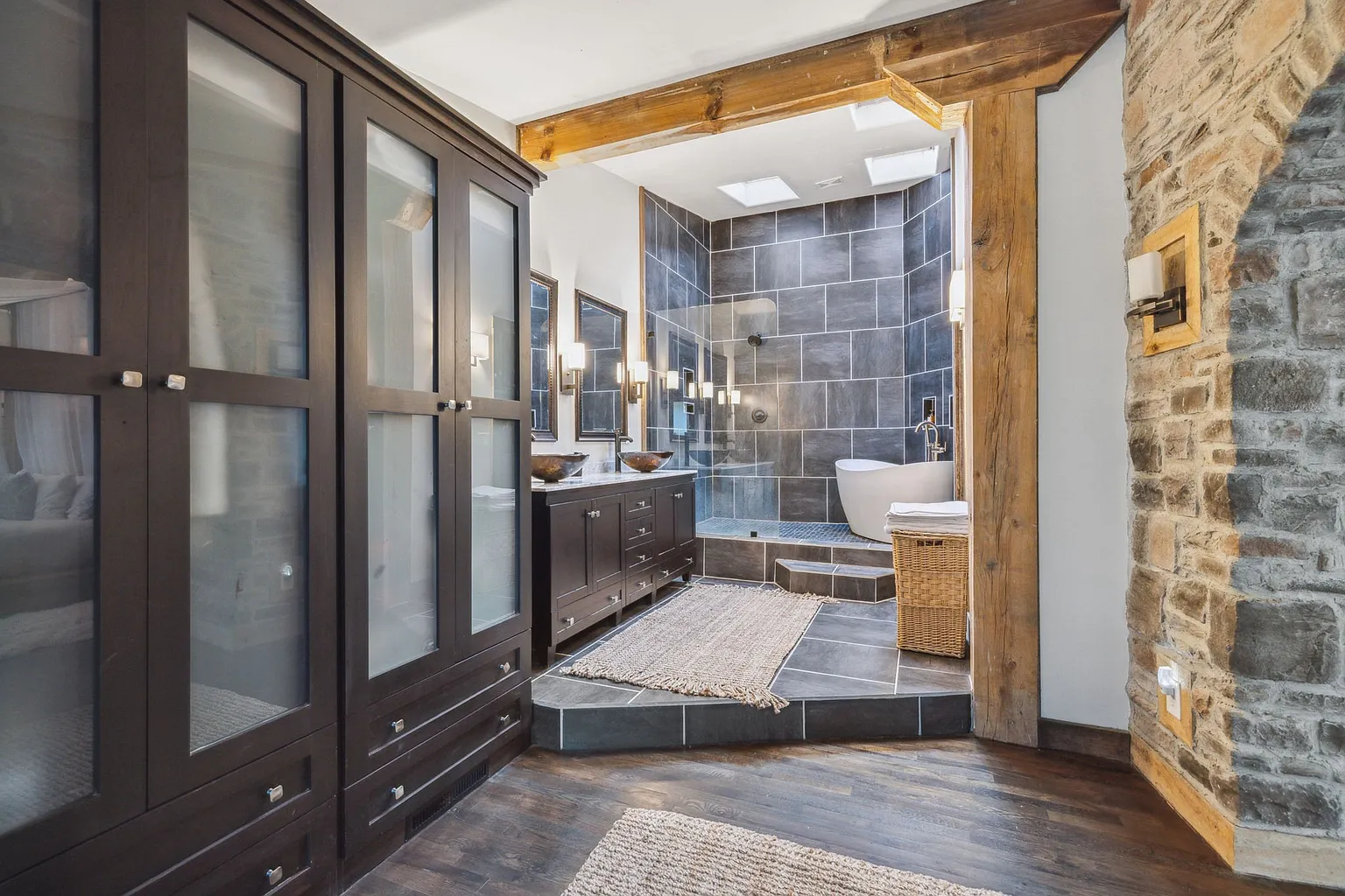 The bedroom also features built-in wardrobes and an en-suite bathroom lined in dark stone tile.