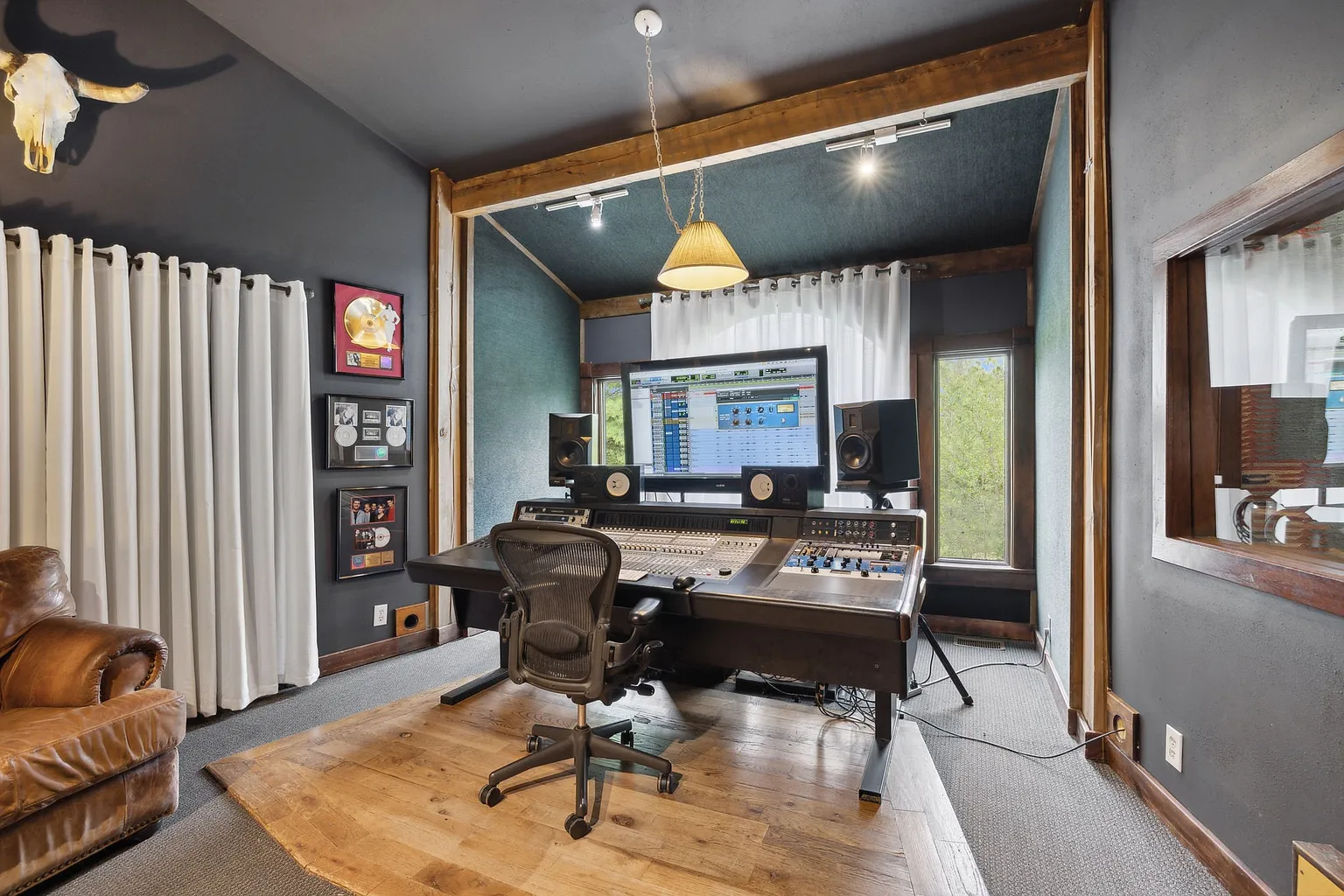 The control room features a professional mixing console, studio monitors, and outboard recording equipment.