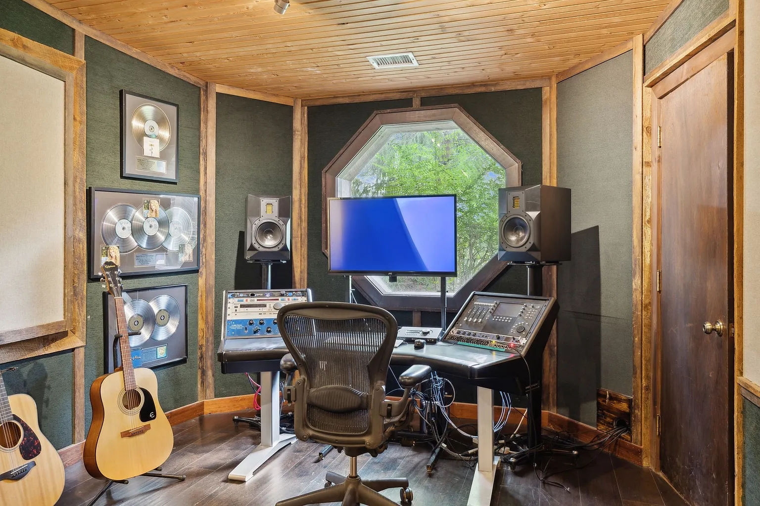 Studio with a dedicated mixing console, studio monitors, recording hardware, and instruments.