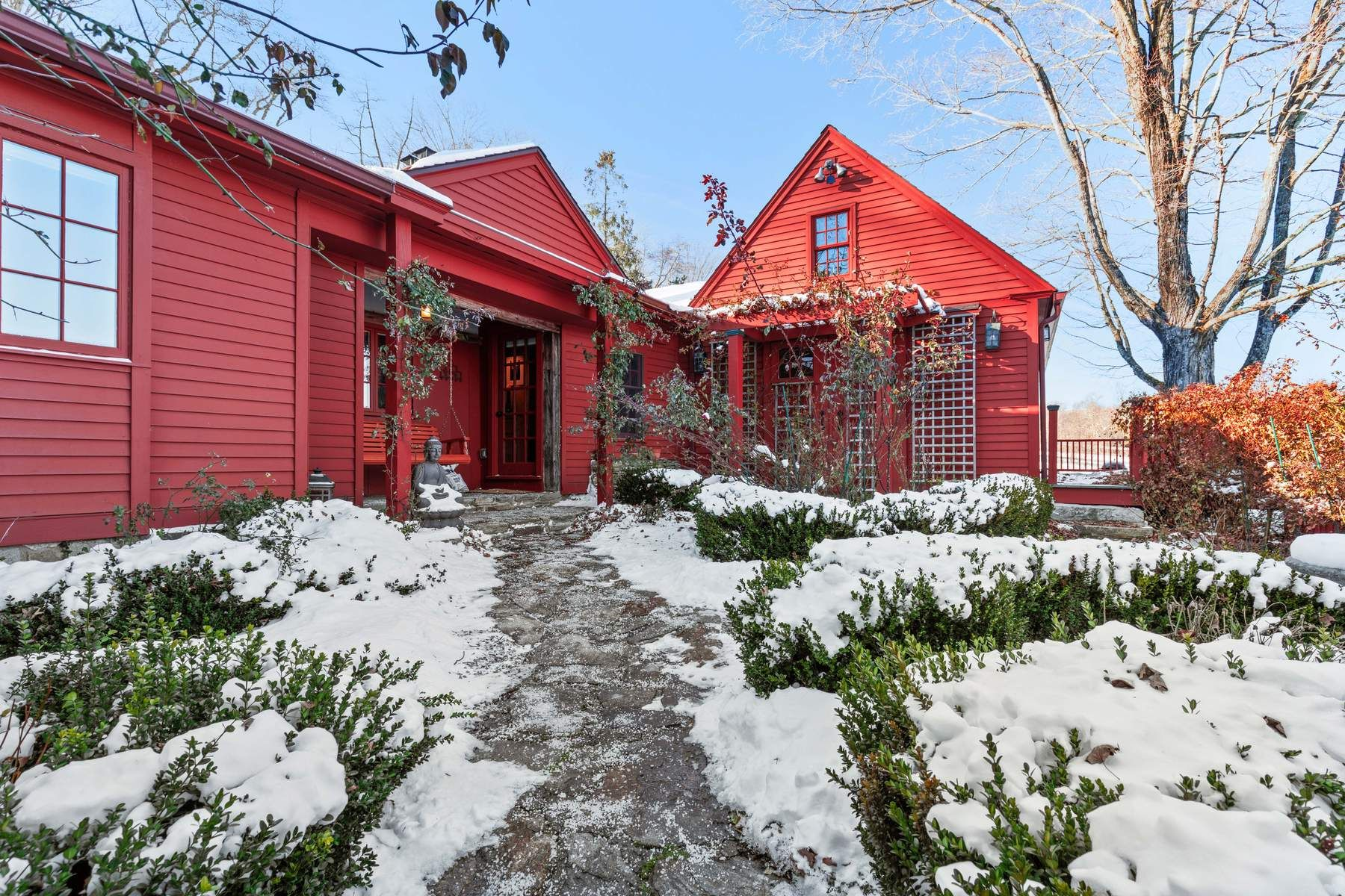 Following the path around to the main entrance, a covered porch wrapped in climbing vines leads to the front door.
