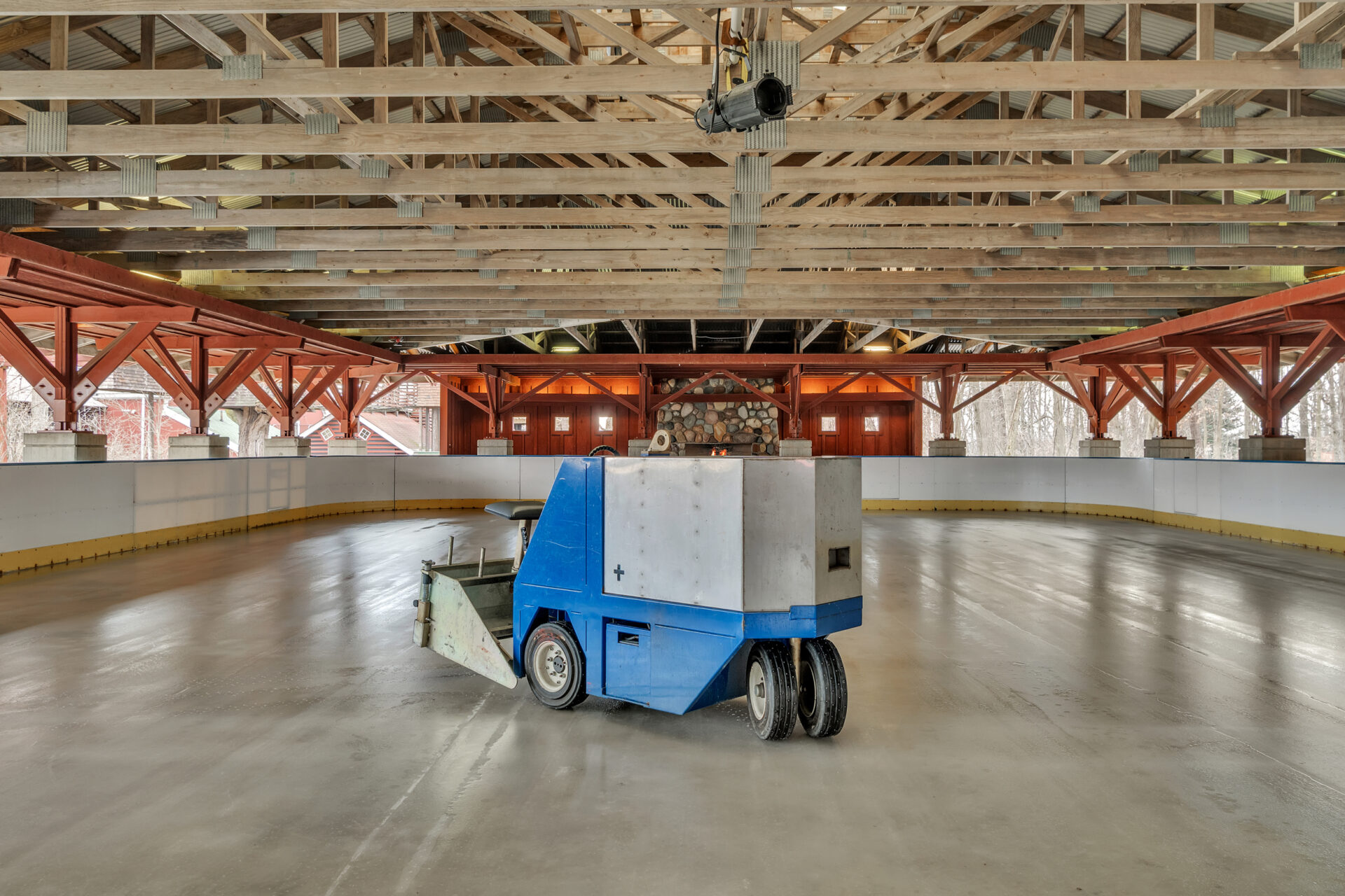 Housed beneath an open timber-framed structure, the ice rink features full dasher boards and even a Zamboni for maintenance.