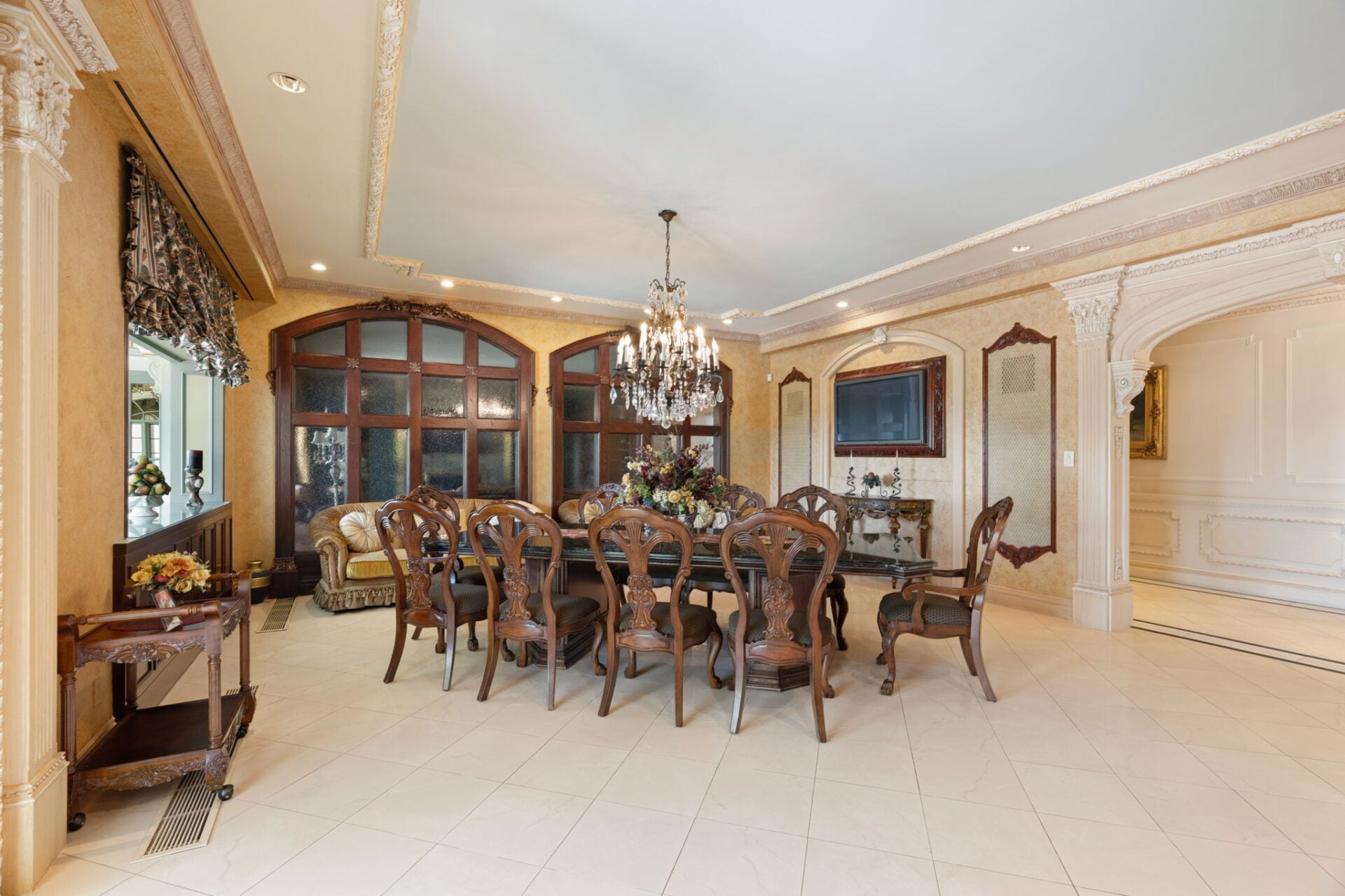Across the room, a casual dining area continues the kitchen's traditional design with 10 wood carved chairs circling a smooth black top table.