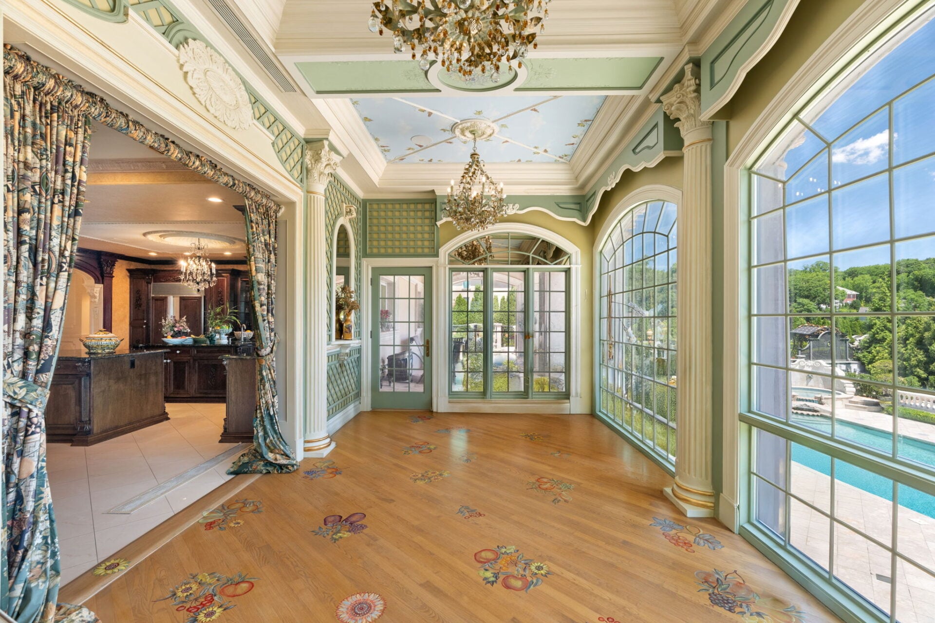 Overhead, pale blue ceiling panels are painted with clouds, vines, and leaves, while the wood flooring is hand-painted with scattered flowers and fruit.
