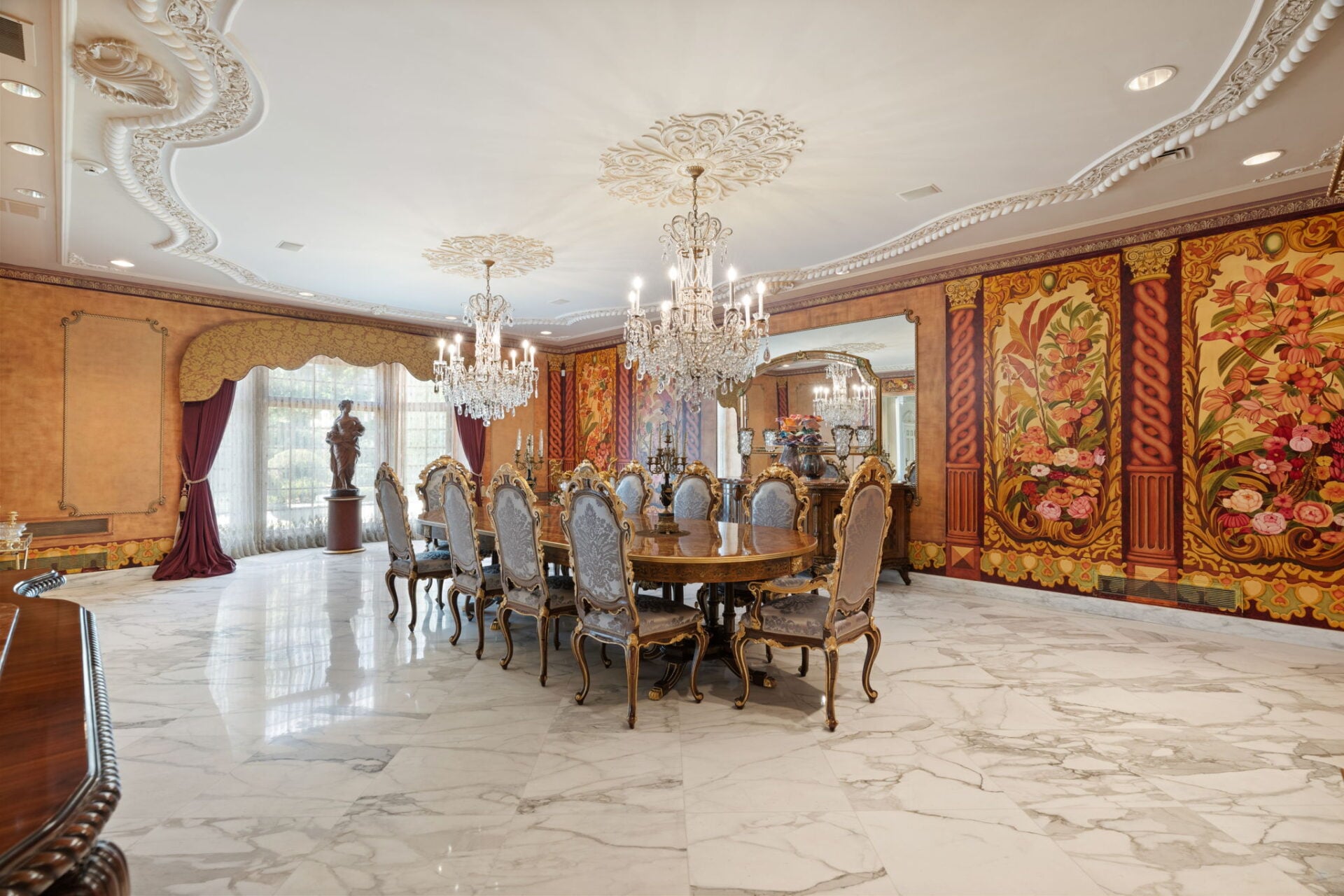 The formal dining room has a much bolder design, with glossy marble floors stretching beneath a long dining table surrounded by gilded high-back chairs.