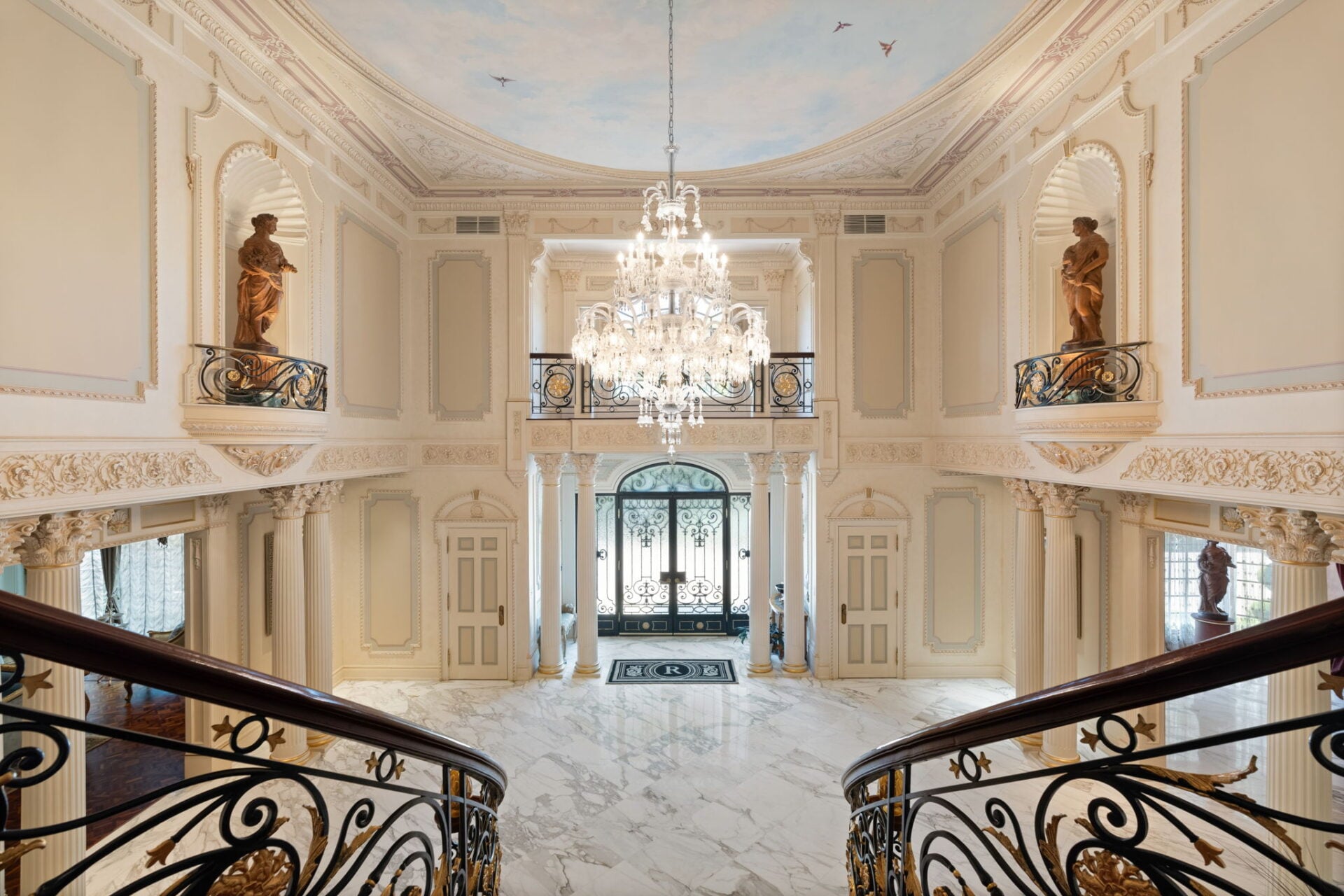 Balconies overlook the foyer from all sides, while arched openings lead into the surrounding main-level rooms.