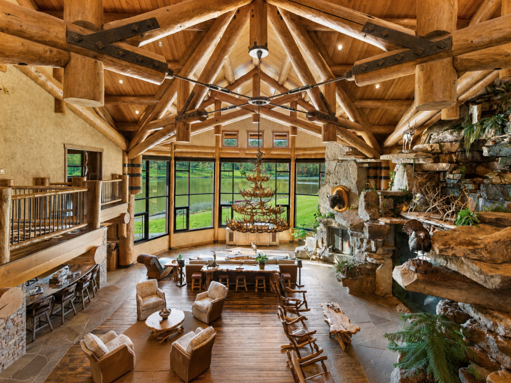 Past the bridge, the space opens into the great room beneath a web of massive log trusses and an antler chandelier.