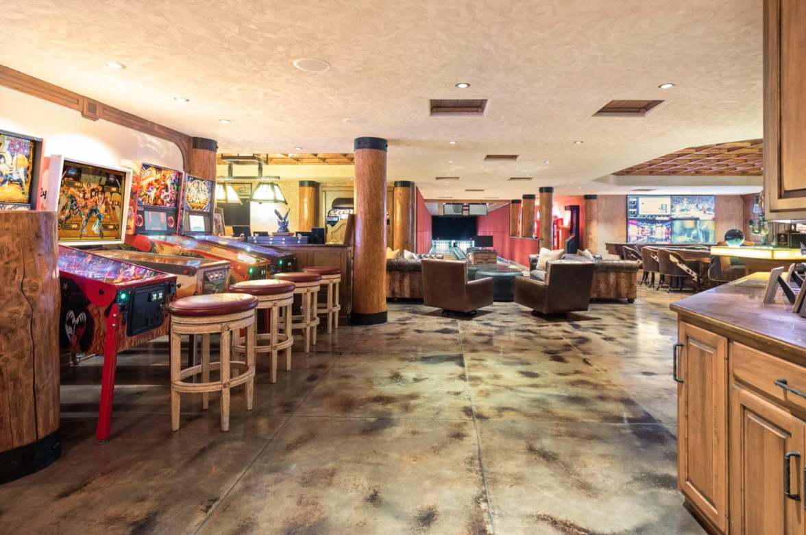 The level begins with an arcade lined with pinball and game machines along one wall, with stools pulled up in front and a lounge area opening in the middle of the room.