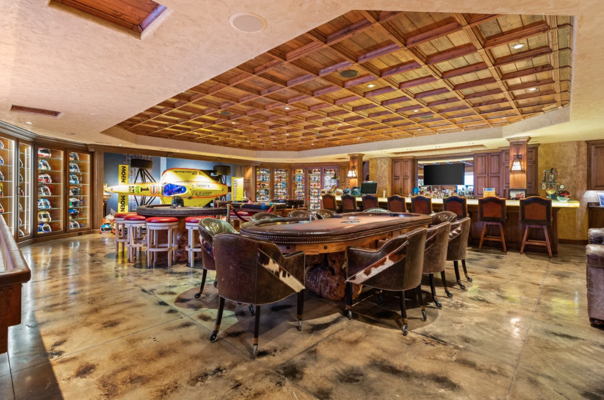 A poker table sits at the center, while a long bar runs across the back with warm onyx surfaces that glow beneath the lighting.