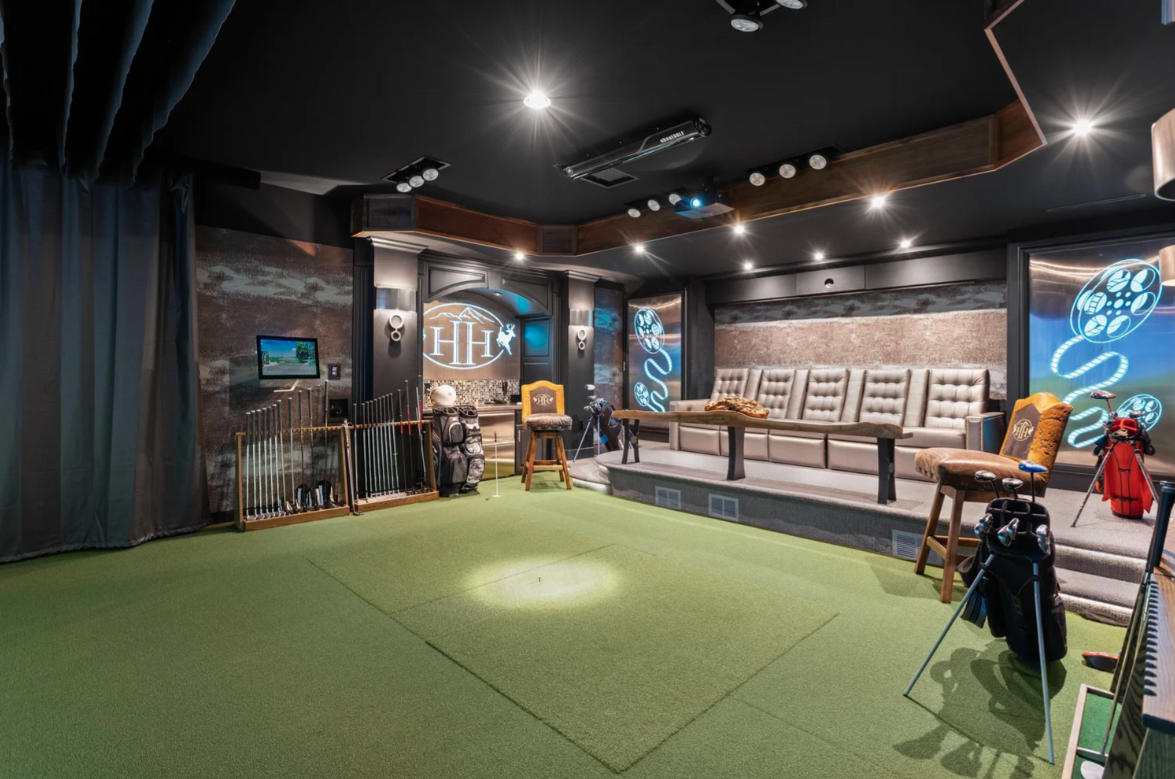 Tucked within its own room is a golf simulator with artificial turf and a hitting area facing a projection screen.