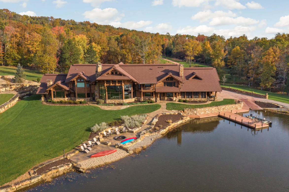 A landscaped shoreline, dock, and small sitting area sit not far from the house