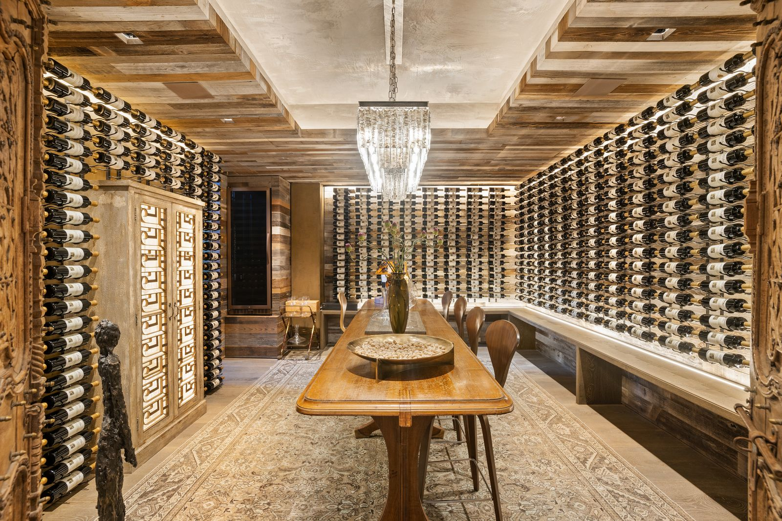 The wine room is entered through a pair of 200-year-old antique doors that open to bottles covering nearly every inch of the walls around a central wood tasting table.