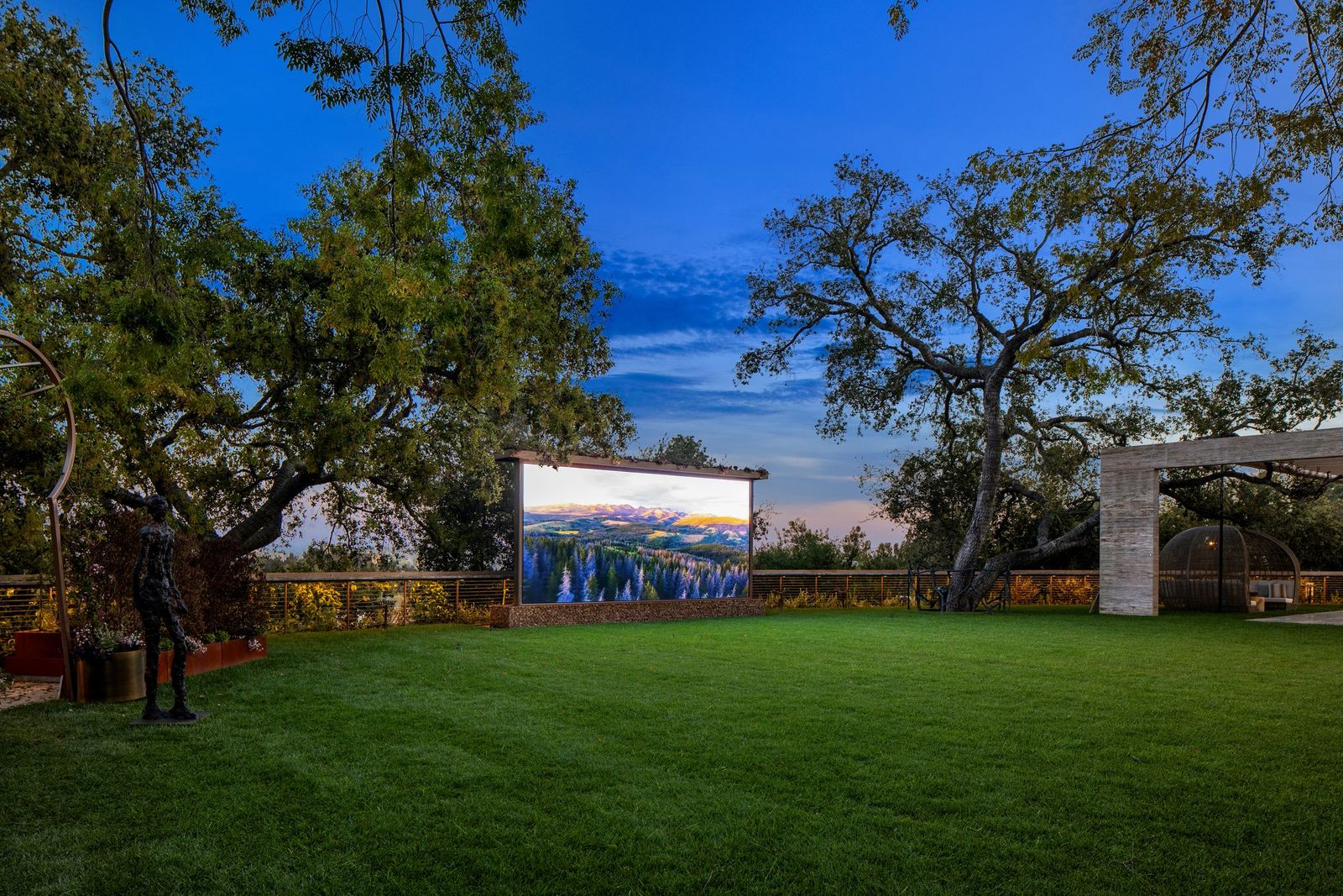 One of the larger lawns is set up as an outdoor screening area, with a large movie screen positioned at the far edge of the grass.