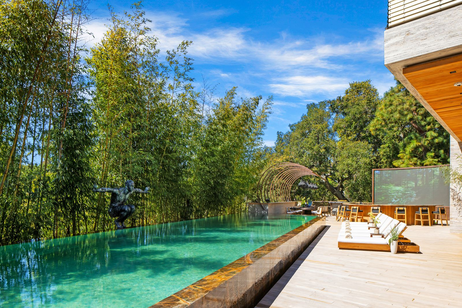The pool itself stretches along a dense wall of greenery, beginning as a long, narrow lap pool.