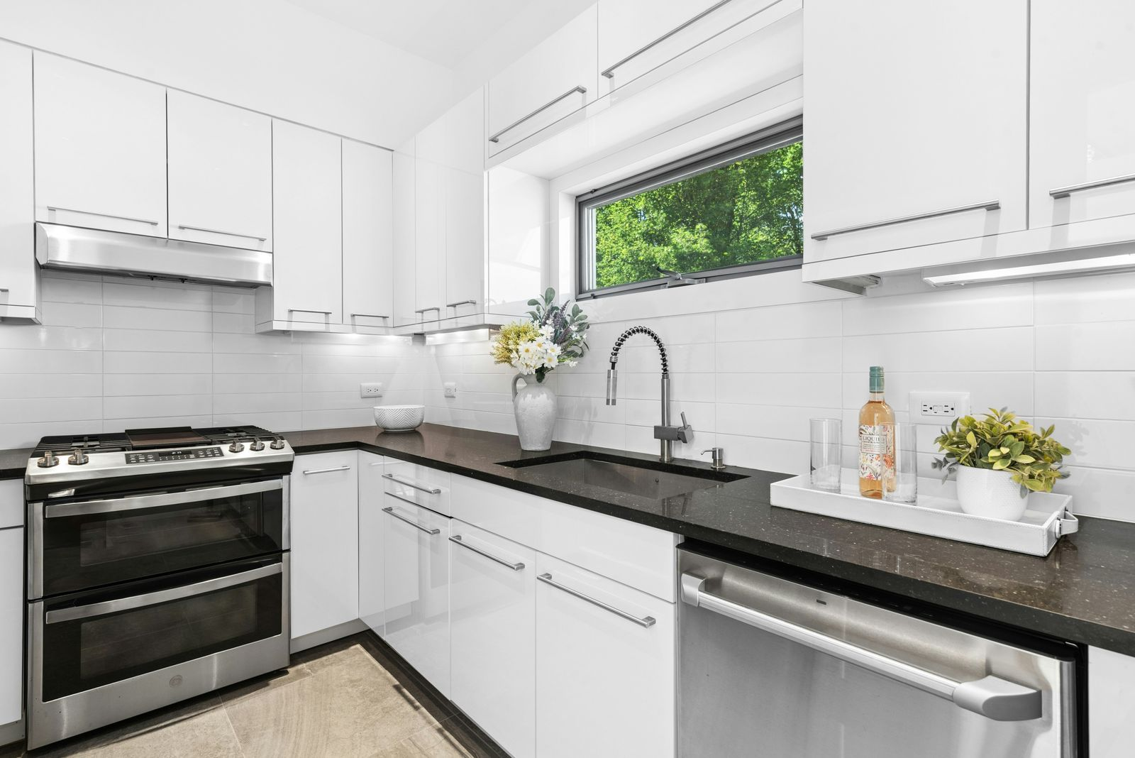 A separate scullery with its own range, sink, dishwasher, and long stretches of counter space beneath a horizontal window.