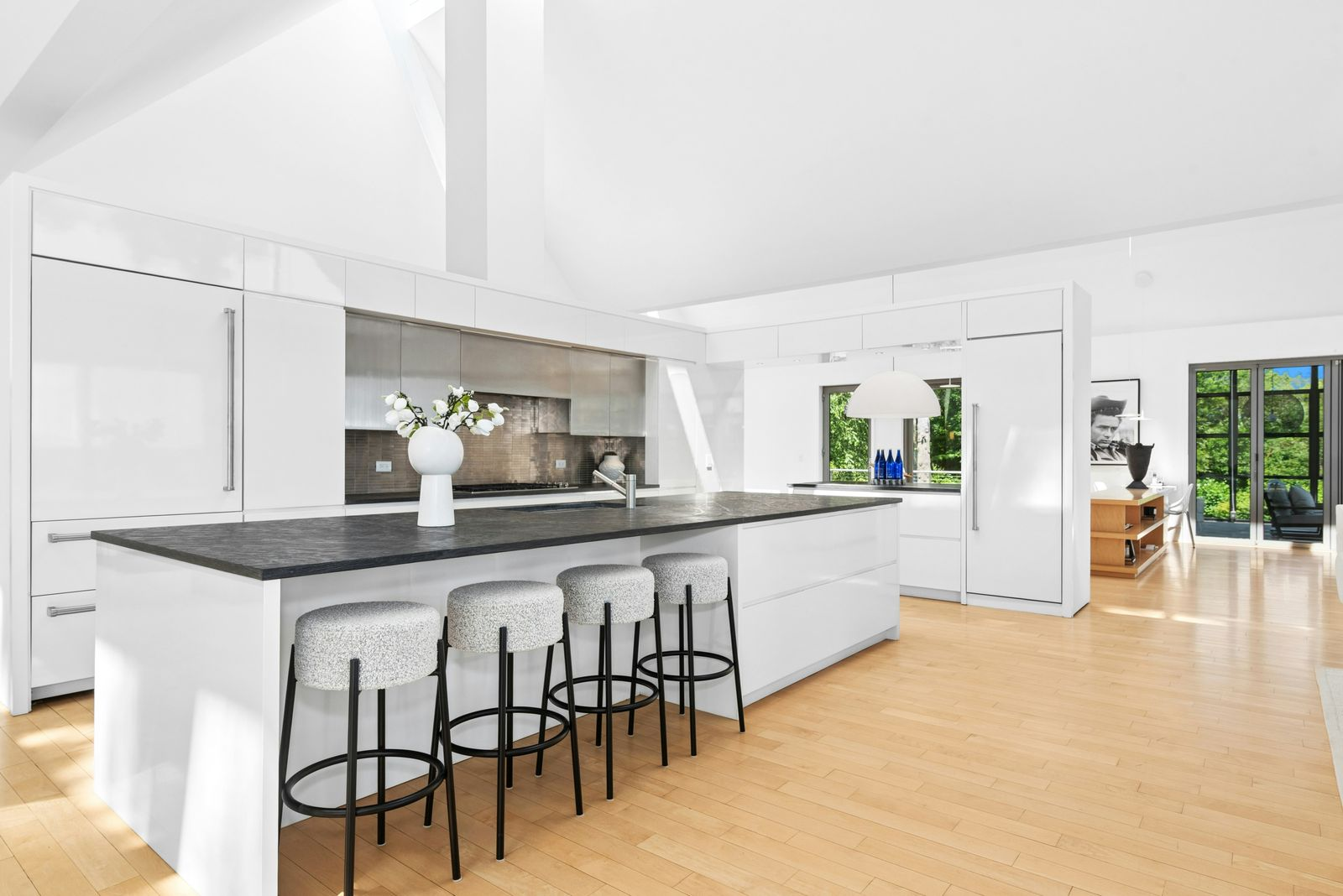Directly across from the dining area, the kitchen is centered on a long dark-stone island with seating for four and a sink built into the work surface. 