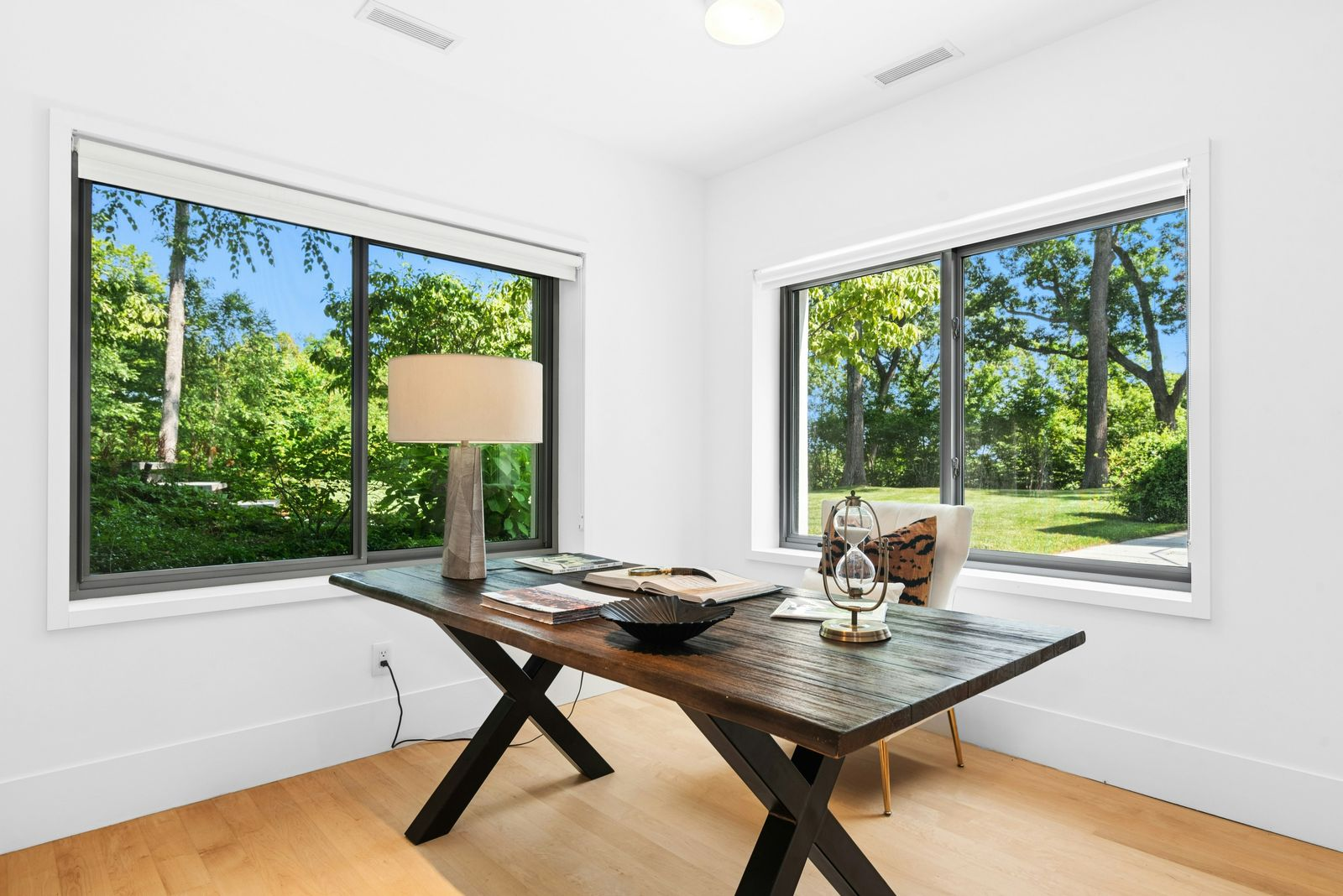 In the corner, the office space features a large wood desk positioned directly between the walls windows.