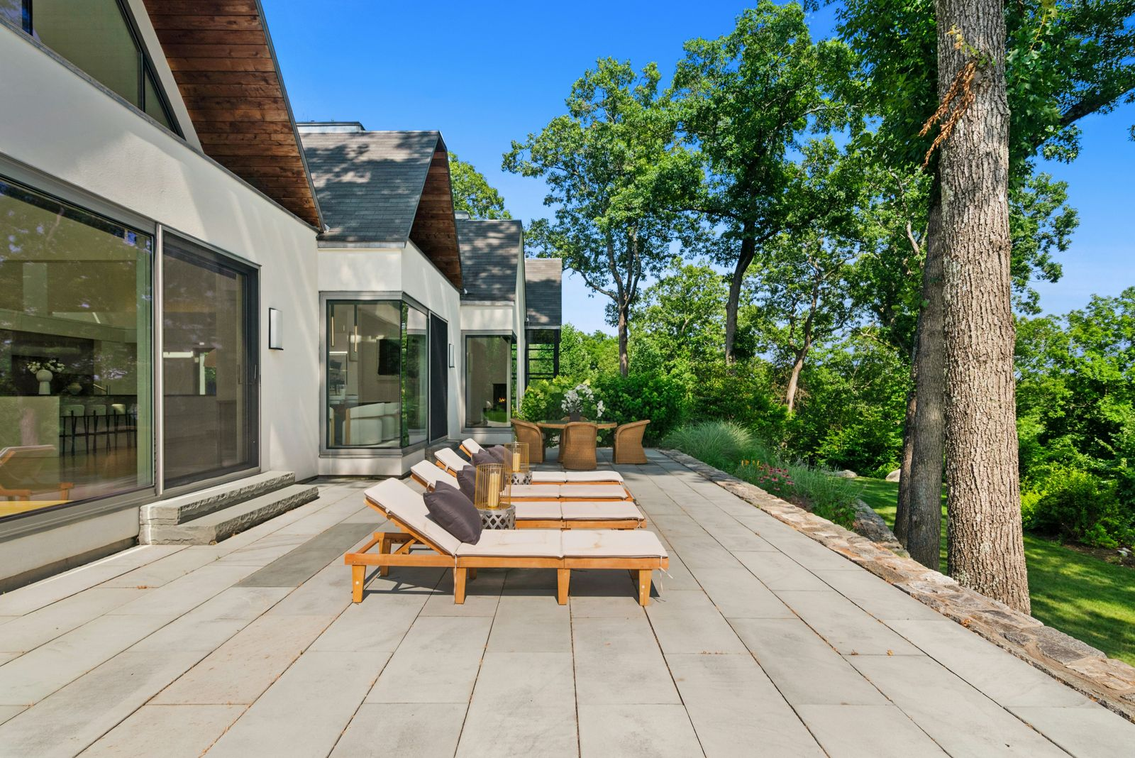A stone terrace runs along the back of the house, with rows of loungers set beside the glass-lined interiors. 