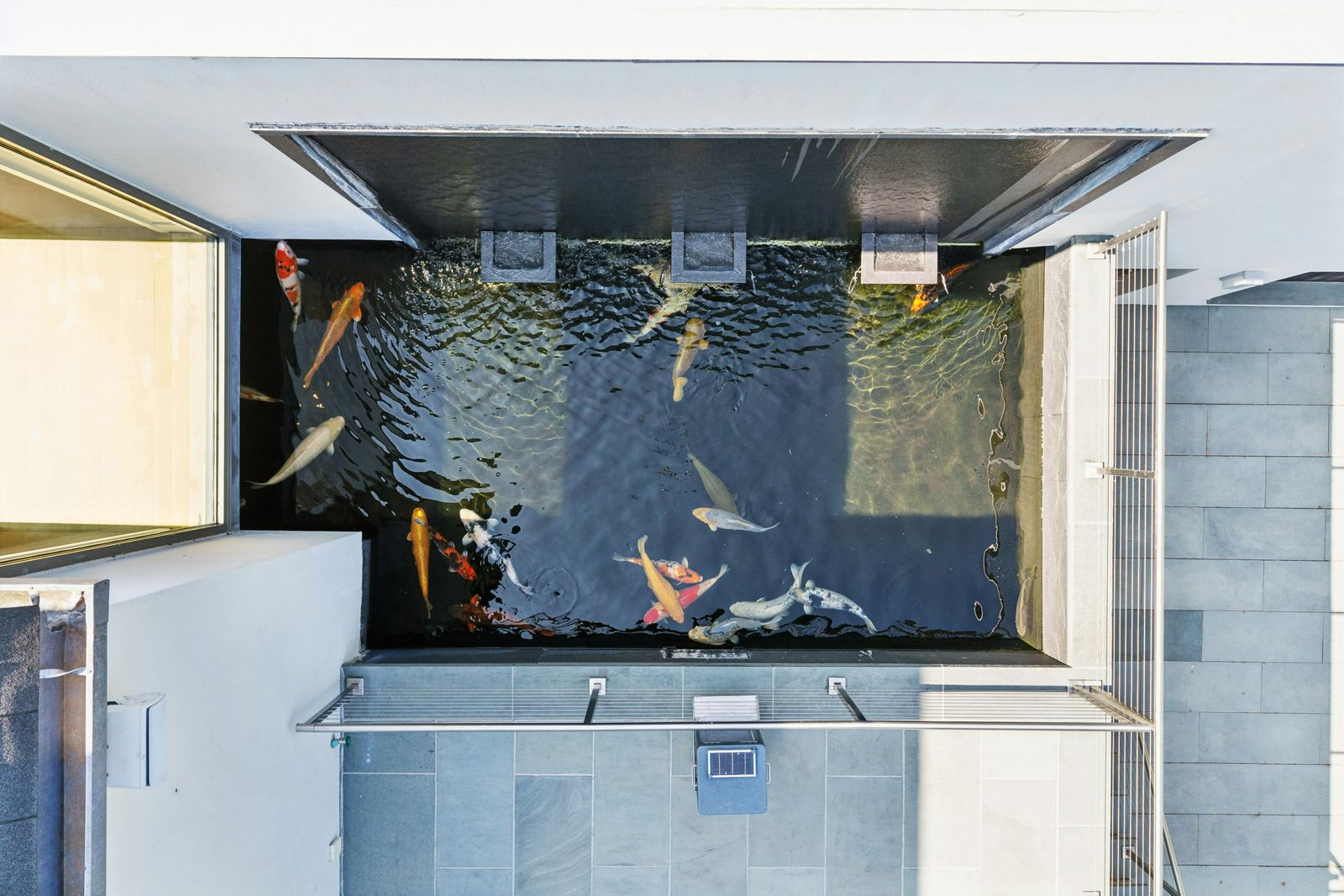 From above, the channels wrap closely around the structure before continuing between the buildings, making the water features part of both the landscape and the home's circulation.