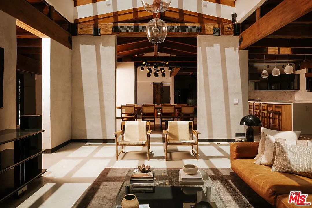 A low leather sofa and pair of lounge chairs face the television, while the room opens toward the nearby dining and kitchen areas.