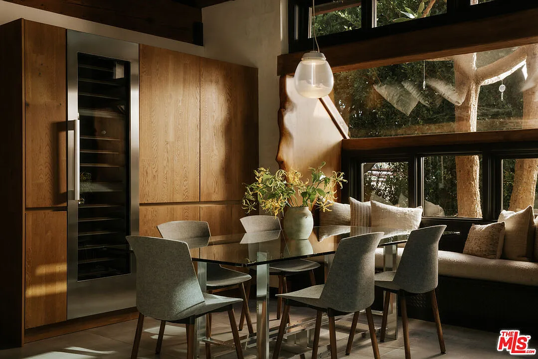 A casual breakfast nook is tucked into a corner of the home, with a glass-topped table surrounded by grey chairs and a built-in banquette running beneath the windows.
