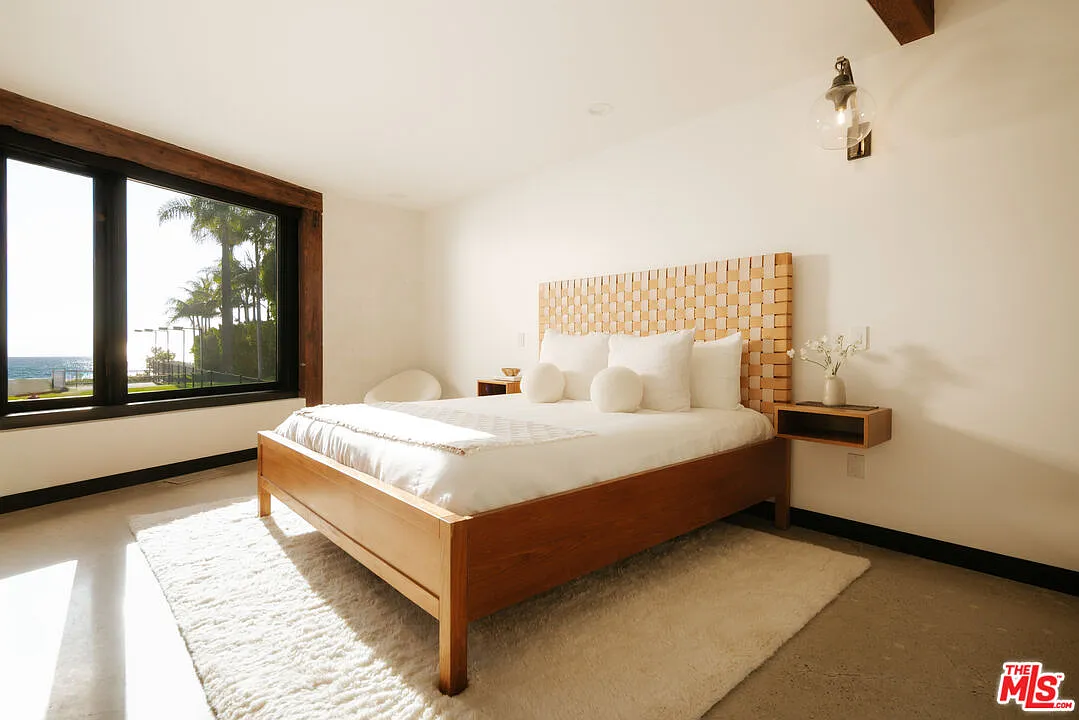 The second bedroom is much brighter with a simple wood bed set against a woven geometric headboard.