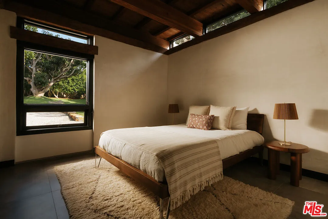The third bedroom returns to the darker timber palette, with a wood ceiling and exposed beams extending above the bed.