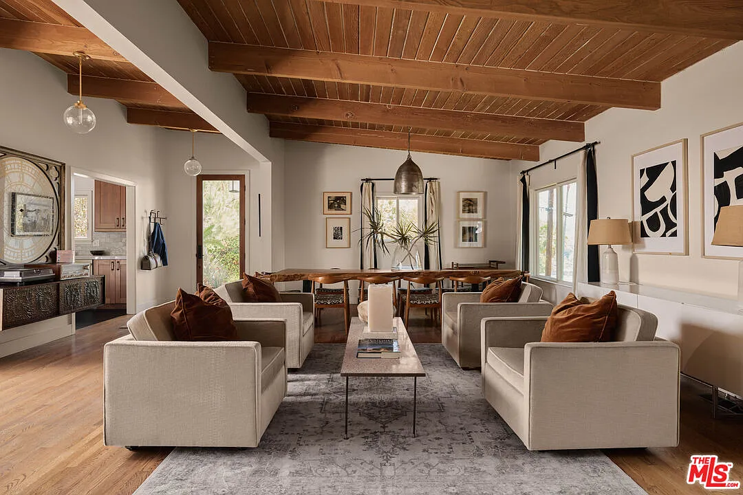 At the center, a conversational seating area creates a natural transition between dining and the more relaxed end of the room made up of four upholstered chairs grouped around a low coffee table.