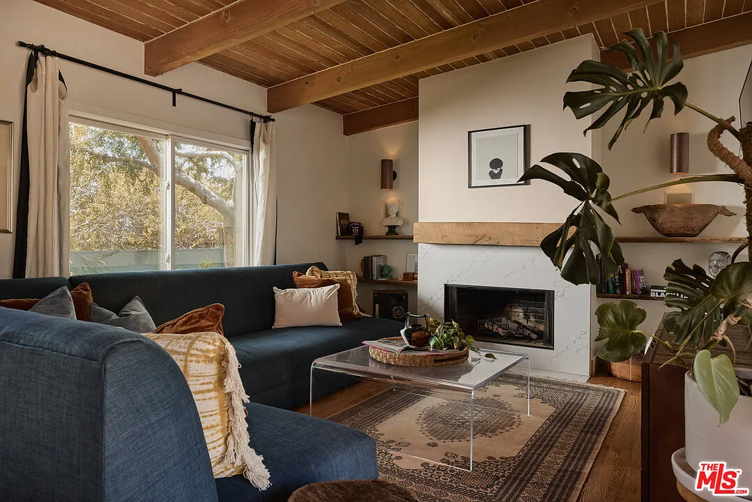 A dark blue sectional wraps around a marble-surround fireplace with a simple wood mantel.
