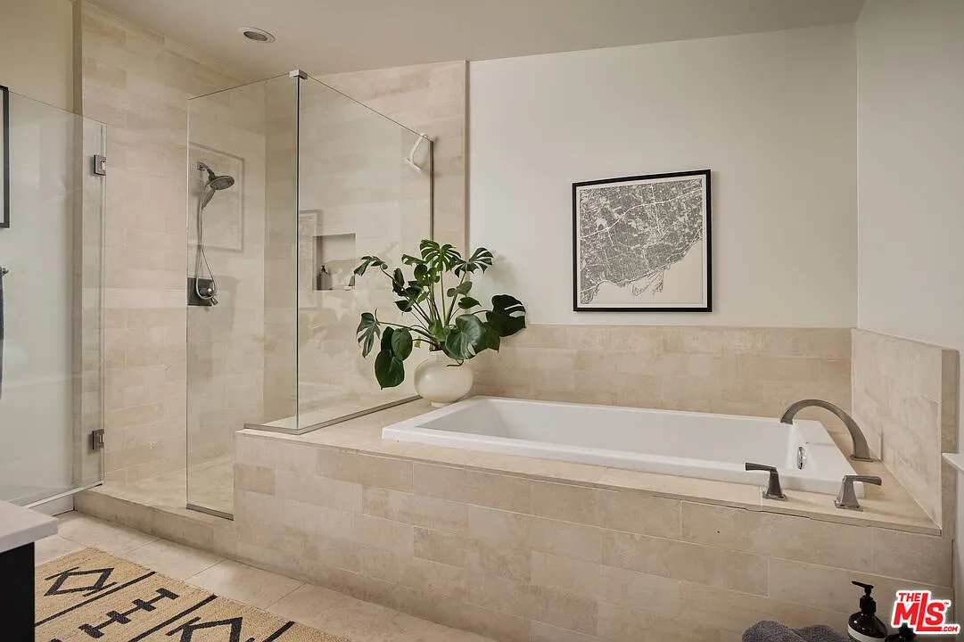 Across from the vanity, a deep soaking tub is set beside a frameless glass shower, creating a spacious bathing area.