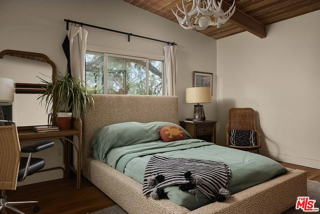The guest bedroom has the most modern design of the three, with a neutral palette and a white antler light fixture hanging over the low bed.
