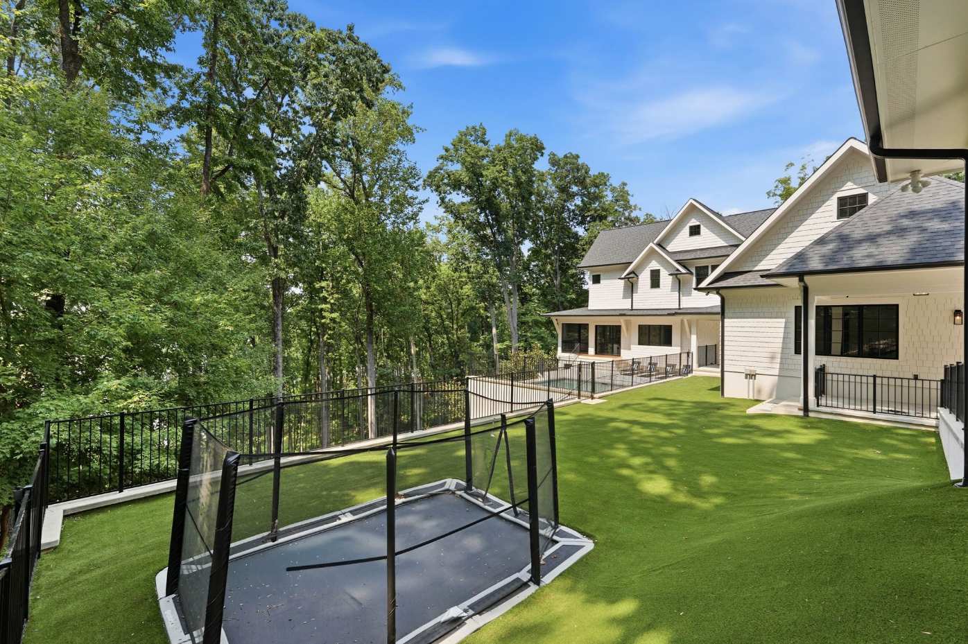 Between the main residence and detached garage is a section of artificial turf with an in-ground trampoline.