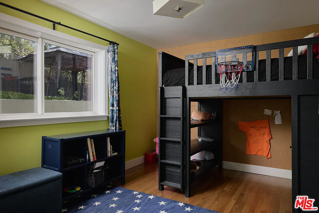 A lime-green accent wall brings another burst of color, while a small basketball hoop mounted to the bed turns the furniture itself into part of the room’s playful design.