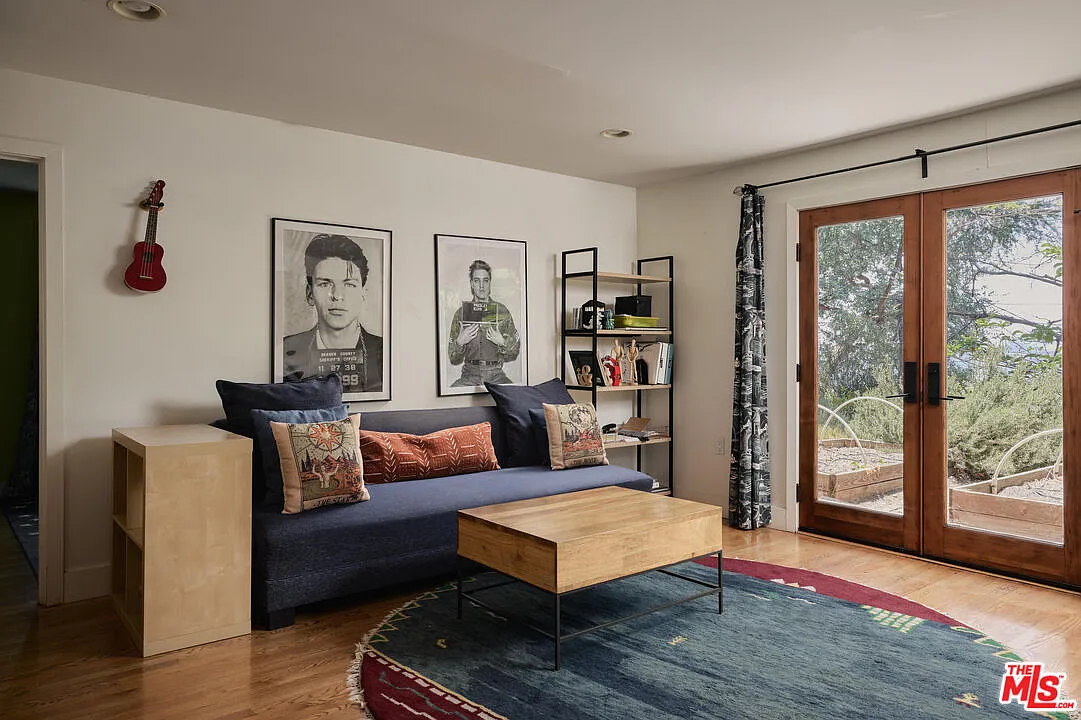 The media room is arranged as a casual screening and listening space, with a deep navy sofa facing a wall-mounted television and a low wood console below.