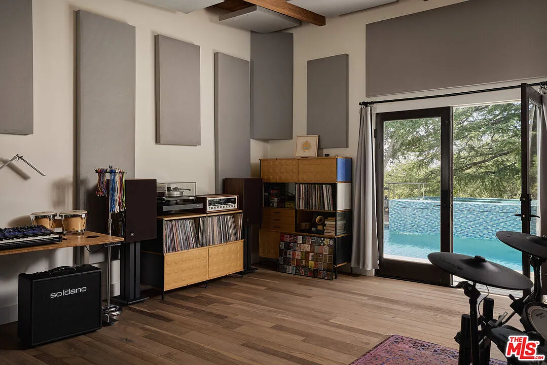 Guitars hang alongside amplifiers, an electronic drum kit, keyboards, and recording equipment, while built-in storage holds an extensive vinyl collection.