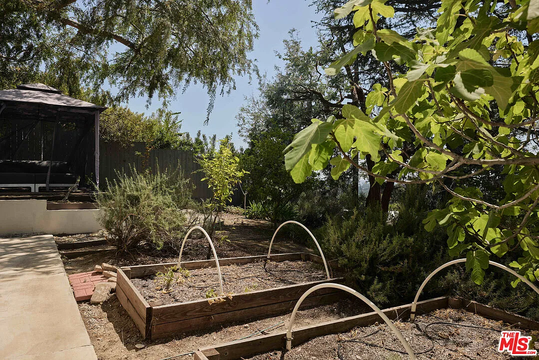 Raised garden beds sit along one section of the yard, while a nearby gazebo creates another tucked-away destination within the grounds.