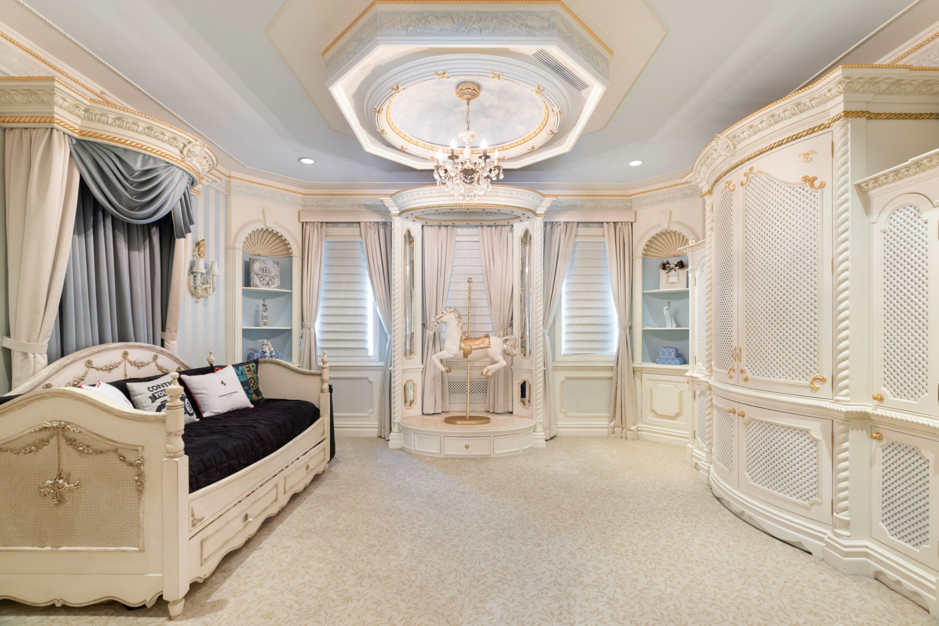 With a much lighter design, the kids' bedroom is painted in pale blue and white with built-in cabinetry, decorative wall panels, and a daybed positioned along one side of the room.