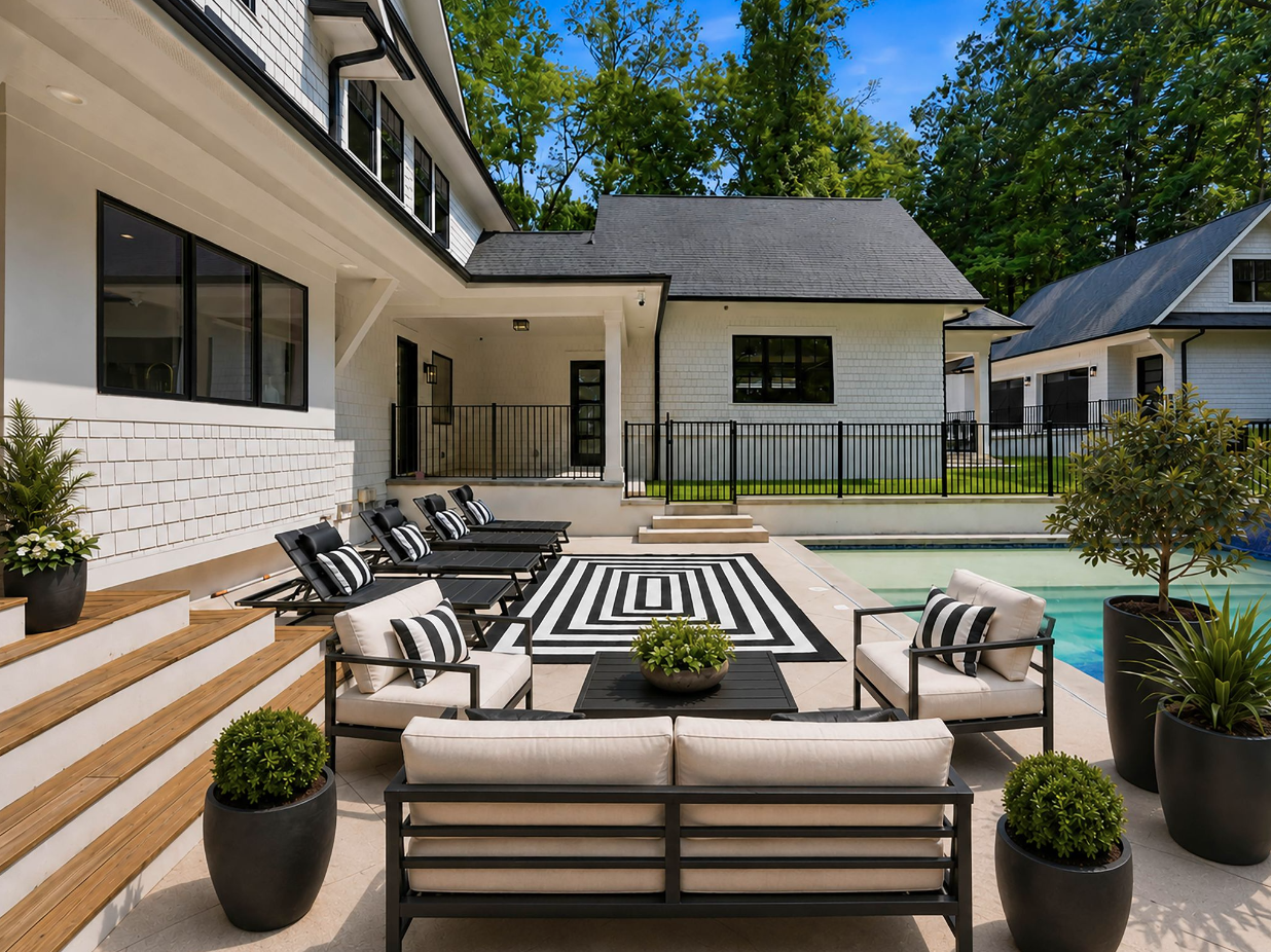 A shallow entry shelf extends across one end, while black chaise lounges and an outdoor lounge extend across the pale concrete deck along the opposite side.