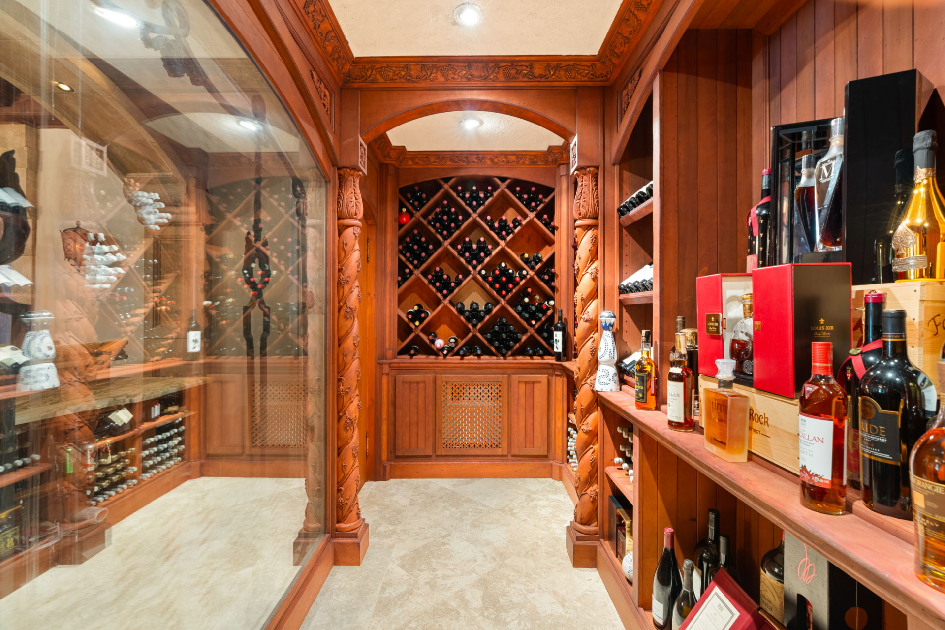 Carved wood columns frame built-in racks along the walls, including large diamond-shaped storage compartments filled with bottles.