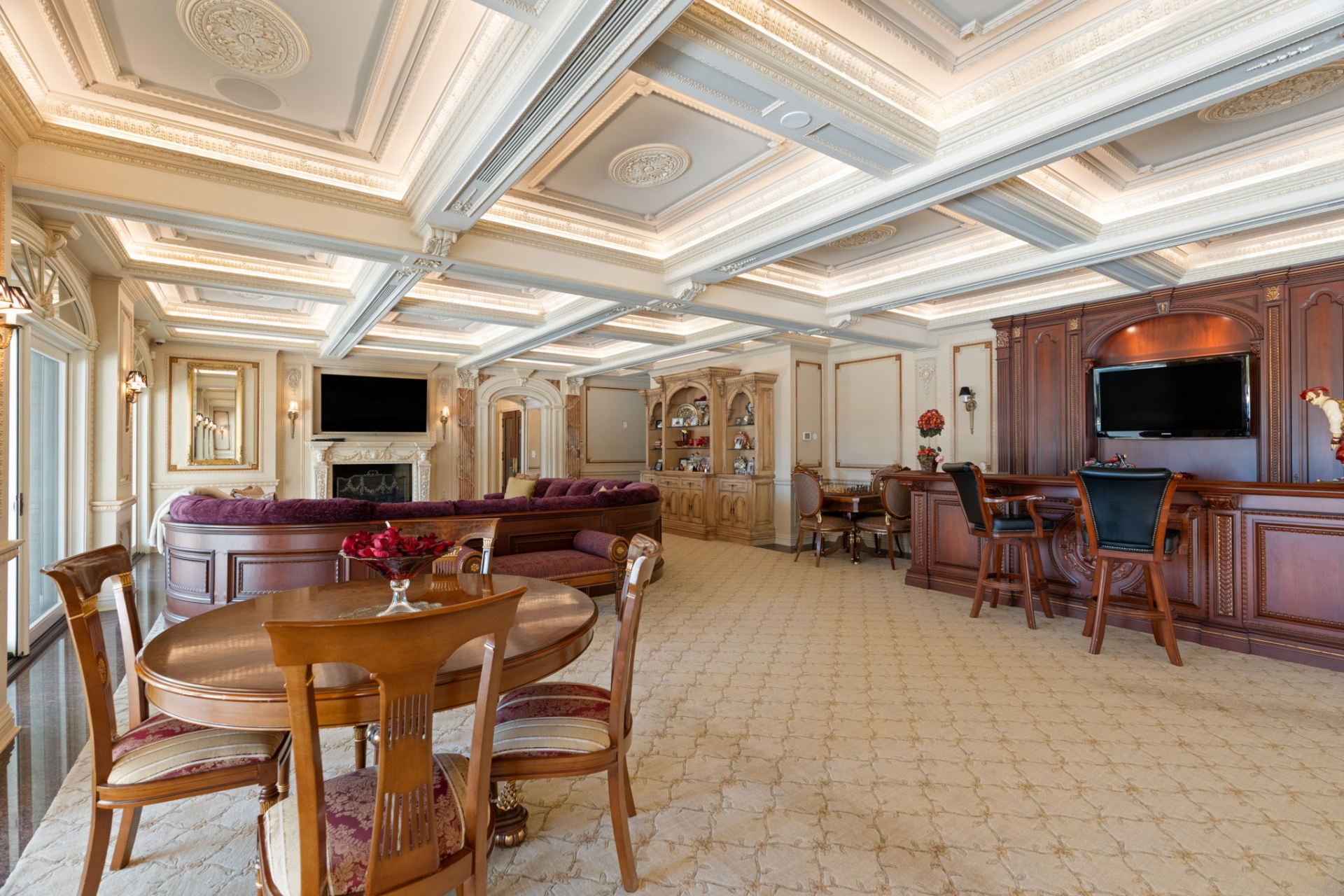 A curved couch faces a fireplace and mounted TV, while additional dining and chess tables create separate places for games or casual meals.