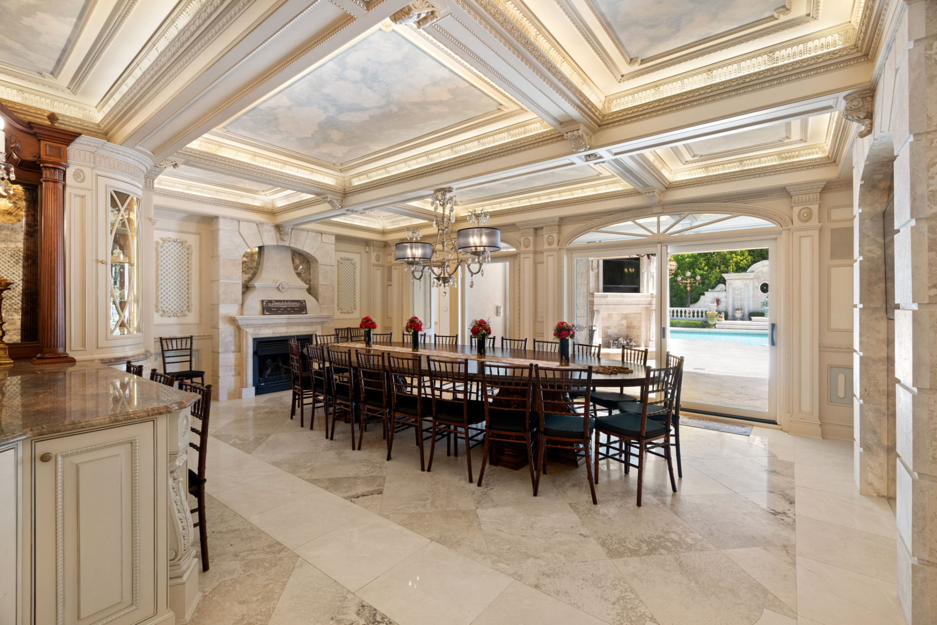 Beyond the main work area, the kitchen continues into a connected dining space that opens directly to the outdoor pool area.