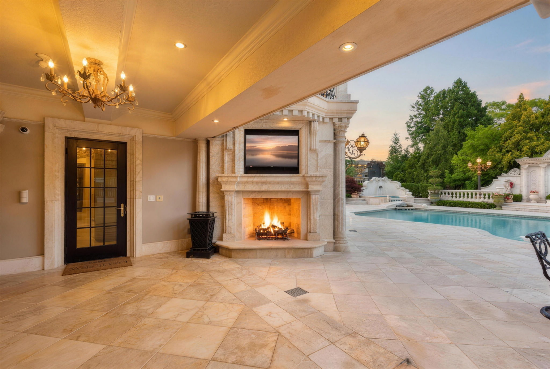 A covered section beside the house includes a stone fireplace with a television mounted above it, offering a covered lounge beside the pool.