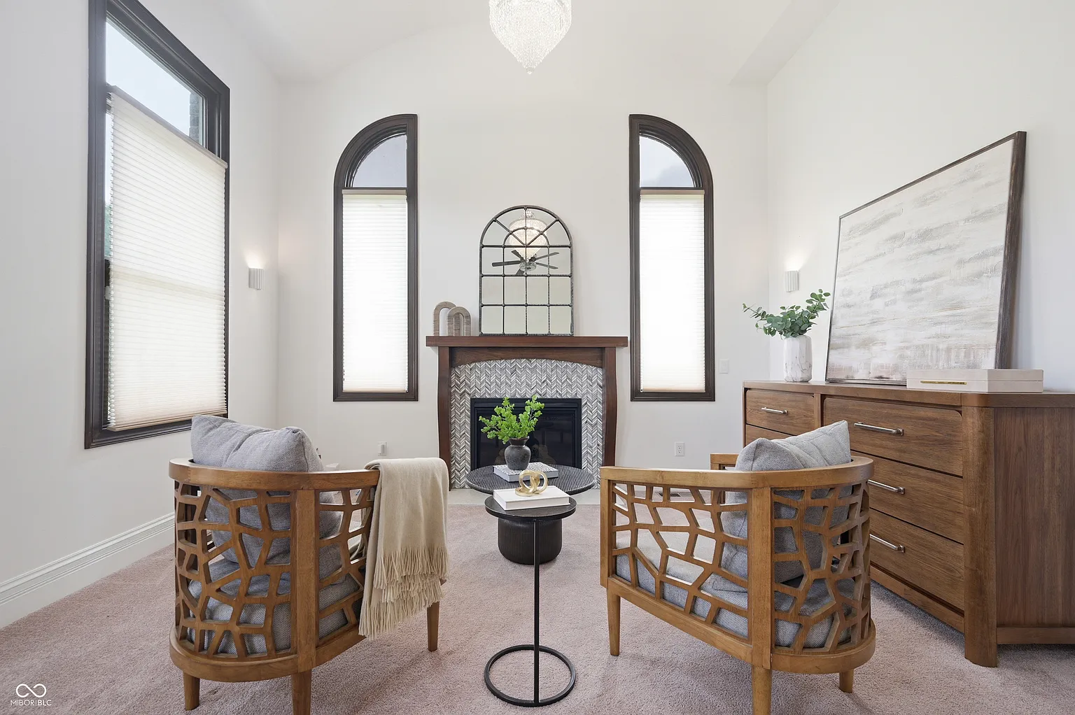 Across from the bed, the suite widens into a small fireside lounge with two wood-framed chairs facing the hearth.