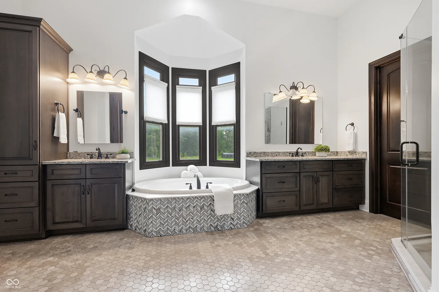 The suite's bathroom continues the dark wood detailing with two separate vanities positioned on either side of a deep soaking tub. 