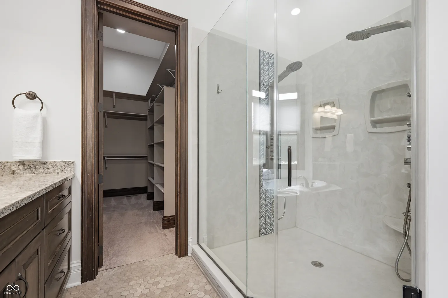 A large glass shower sits just before a walk-in closet.