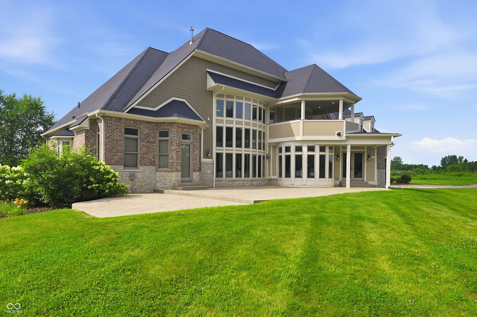 Beyond the patio, the property opens into a wide lawn that stretches away from the house.