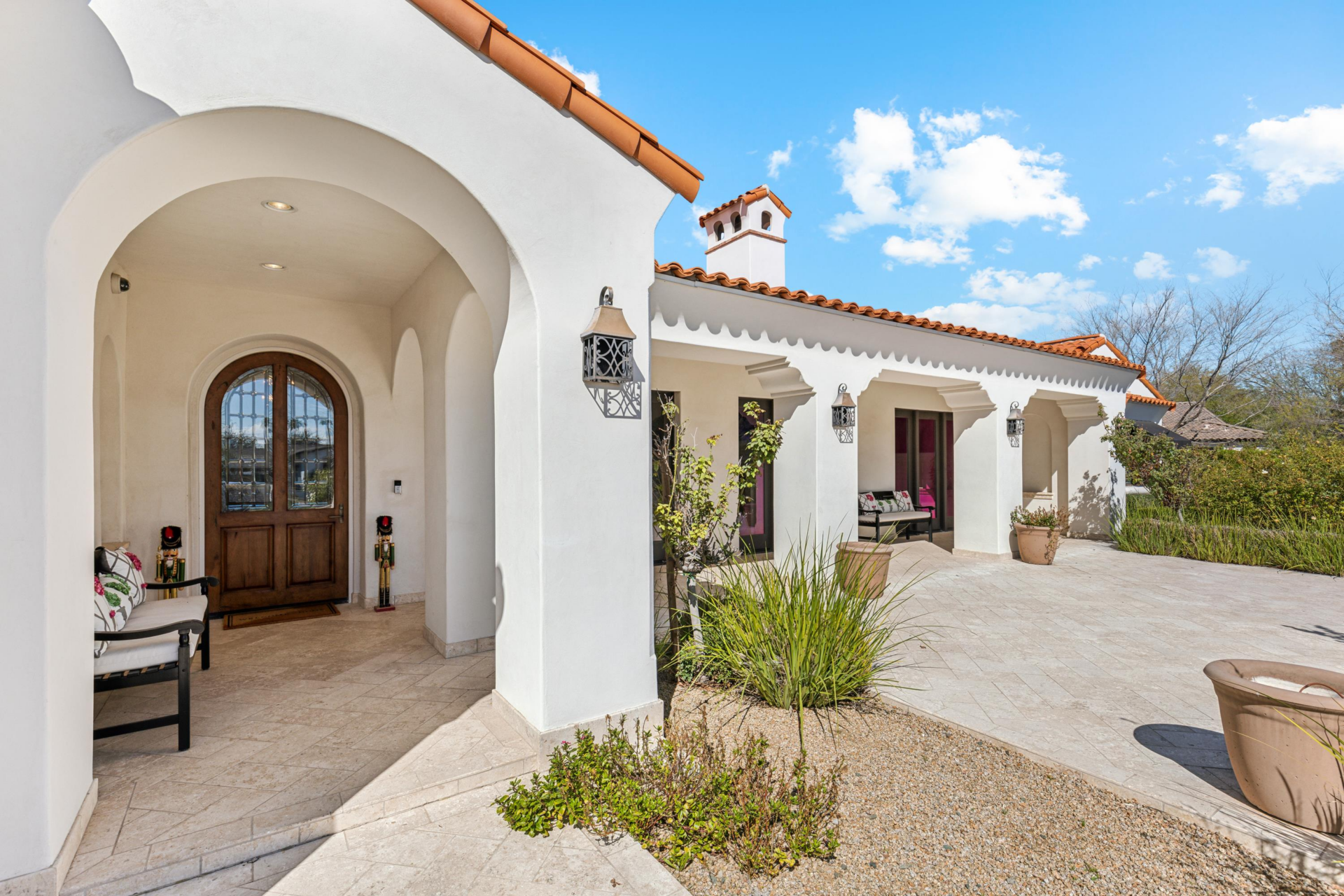 Next to the patio, the entry sits beneath a rounded stucco arch, where a curved wood-and-glass front door welcomes you inside.