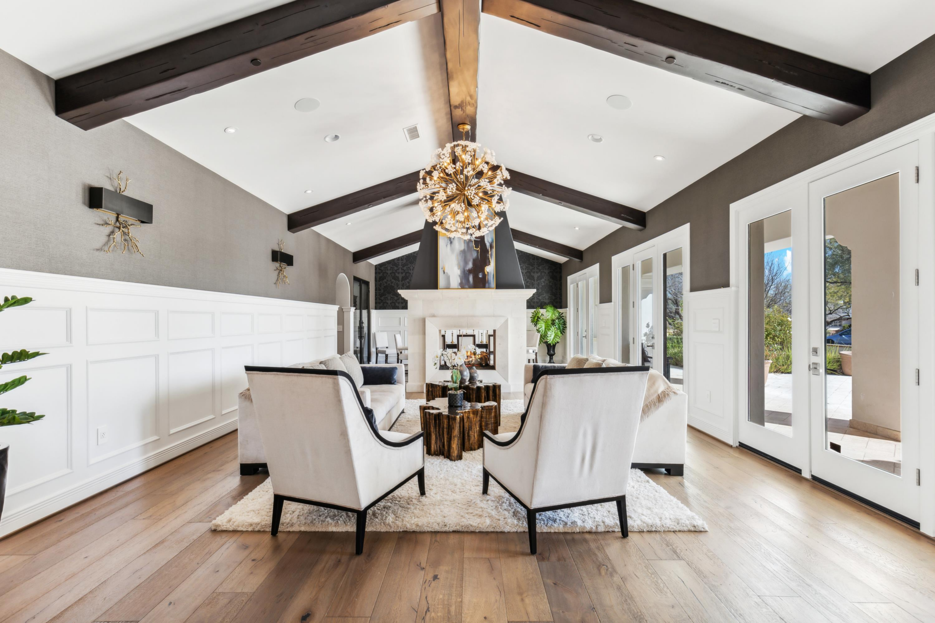 A double-sided great room positioned just to the right of the entrance, where the formal living and dining spaces are divided by a two-sided European stone fireplace.