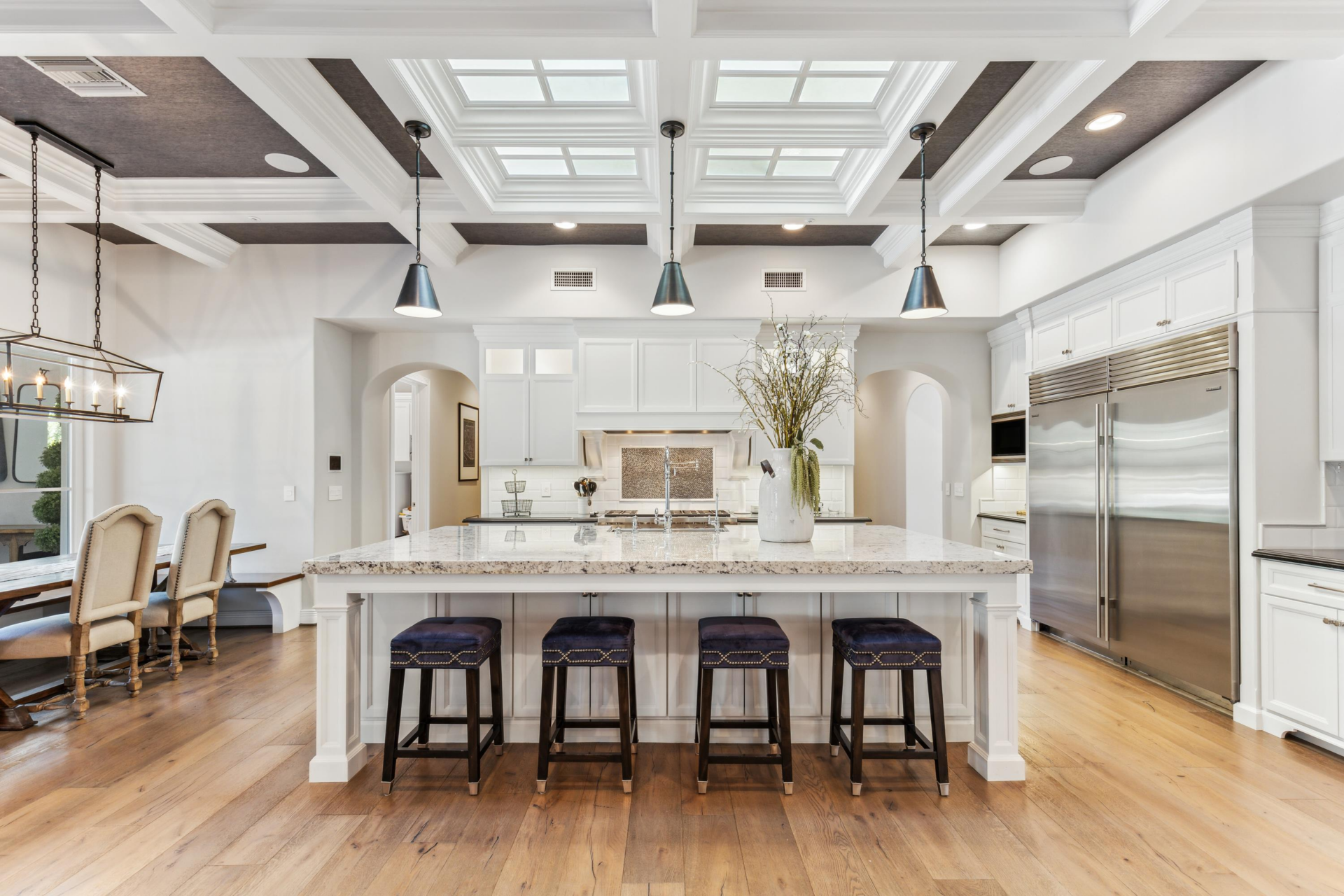 Across from a built-in breakfast nook, the center island has bar seating along one side and a deep farmhouse sink built into the other. 
